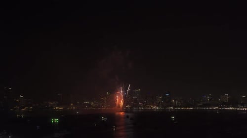 Fireworks Exploding Over City and Ocean at Night