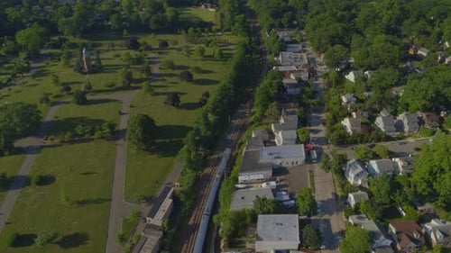 Vista aérea de un tren que pasa cerca de un parque y un vecindario suburbano en Nueva York