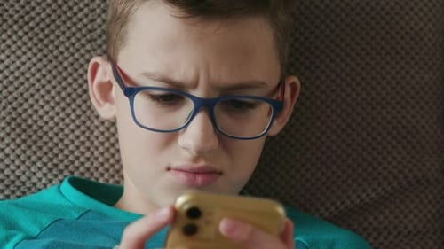 Boy with Glasses Looking at Phone