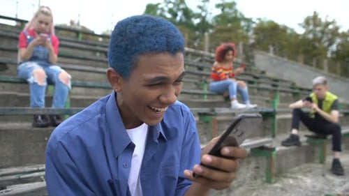 Teenagers Using Mobile Phones on Stadium Seating