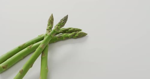 Video of close up of fresh asparagus with copy space over white background