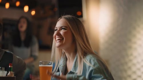 Closeup of a Group of Male and Female Friends Sitting Together in a Bar and Watching a Broadcast on