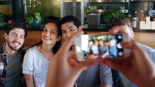 Woman clicking photo of friends on mobile phone