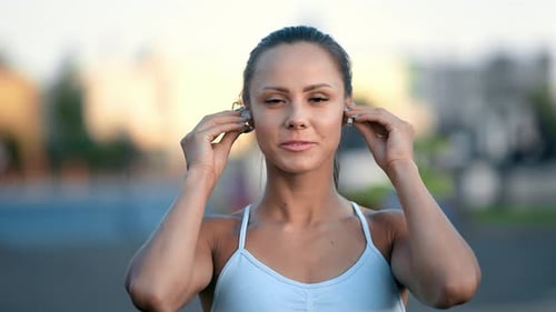 Woman Inserts Wireless Earbuds Before Workout