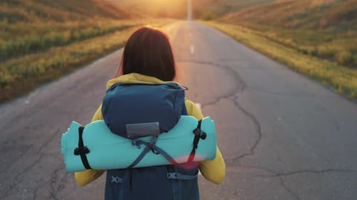 Female Hiker Walks Down Rural Road at Sunset