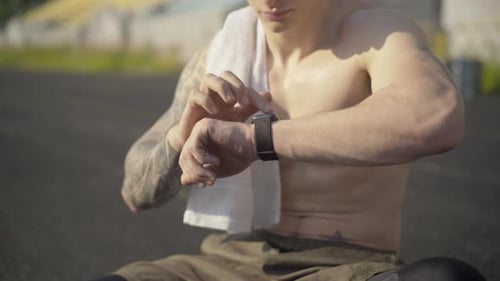 Muscular Man Using Smart Watch After Workout