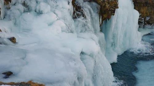 Gros plan du fond de la cascade gelée avec des roches glacées et coulant dans l'eau
