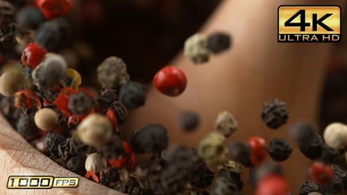 Colorful peppercorns falling into wooden bowl, seasoning concept