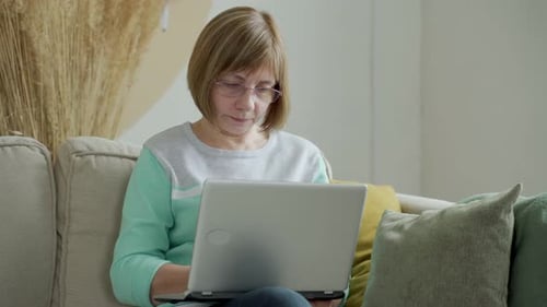 Woman with Blonde Hair Uses Laptop on Couch
