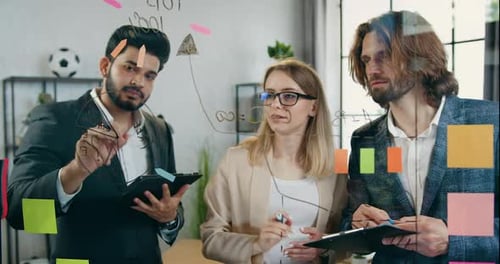 L'équipe travaille ensemble sur un projet de démarrage et enregistre des idées sur un mur de verre dans un bureau moderne