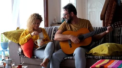 Man Plays Guitar for Woman at Home