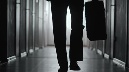 Silhouette of Person Walking Down Hallway with Briefcase