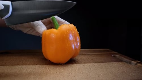 Cutting a Fresh Orange Bell Pepper on Board