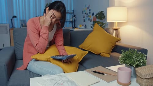 Lady feel stress worried with bill and invoice credit card calculating money on sofa at home night