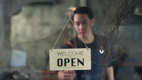 4K Asian man coffee shop owner turning hanging open sign to closed on the door