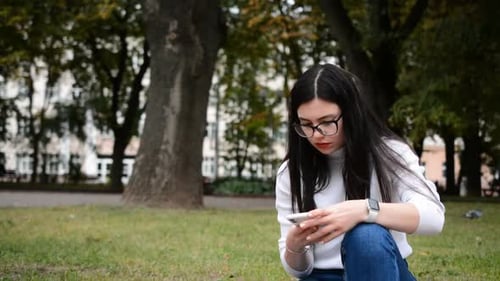 Portrait Of Attractive CaucasianWoman Smiling Brunette Typing Sms In Park