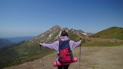 Au sommet du mont Woman, un randonneur lève les mains et admire la nature depuis une vue arrière