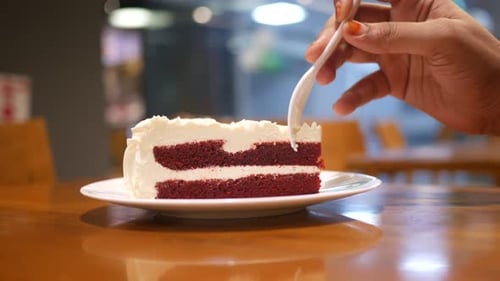 Women Hand Cutting Red Velvet Cake with Spoon at Cafe