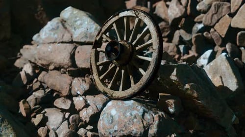 Old Wooden Wagon Wheel Resting on Rocks