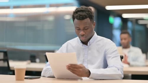 African Businessman Reading Documents in Office