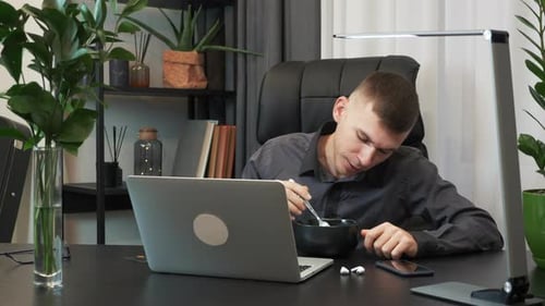Young businessman is having lunch at his modern office and talking by webcam on internet