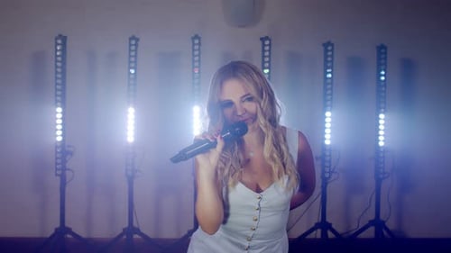 Woman singing and dancing on stage with lights
