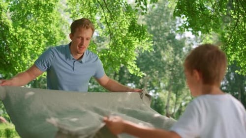 Family Spreading Picnic Blanket in Sunny Park