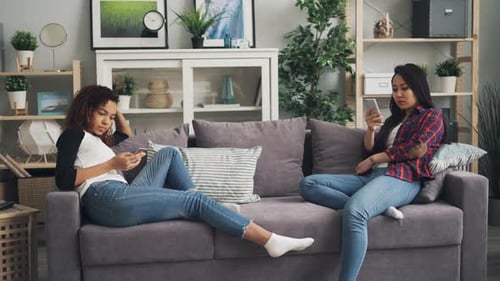 Women Using Smartphones on Couch Indoors