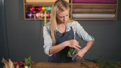 Woman Arranging Fresh Flowers at Wooden Table