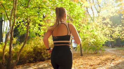Woman Running and Drinking Water in Autumn Park