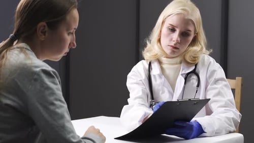 Doctor Consults with Patient, Taking Notes on Clipboard