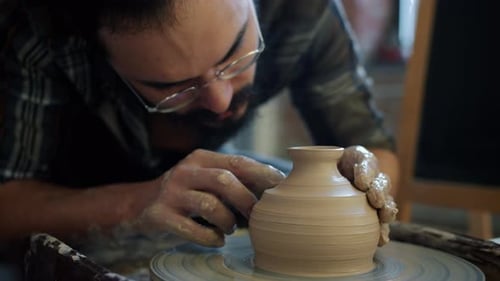 Gros plan de Skillful Potter décorant un bol en céramique sur une roue à lancer travaillant seul
