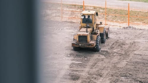 An Old Bulldozer on Rubber Wheels Works on Construction Site.
