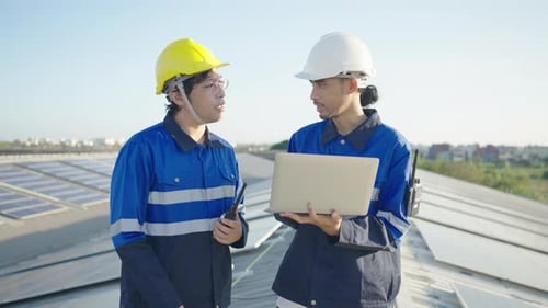 Asian technician inspection solar cell panels field of on roof top factory.
