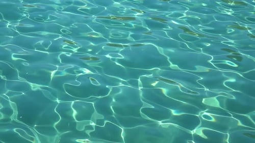 Turquoise Sea with Clear Water, Sand and Small Fish Are Visible at the Bottom. Slow Motion. Close Up