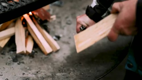 Man Carving Wood with Knife for Fire