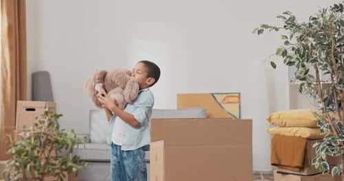 A Little Smiling Sweet Boy After Moving Into a New Apartment Searches Among the Boxes of His Toys