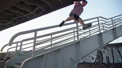 Young Man Parkour Jumps Off Bridge in Urban Area