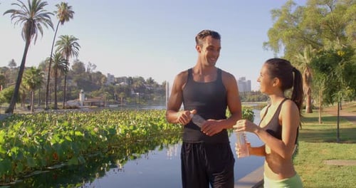 Couple Hydrates After Workout in Sunny Urban Park