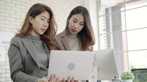 Two Women Collaborating on Laptop in Modern Office