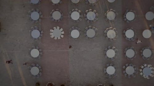 Aerial view of people preparing tables and chairs for a outdoor party in Greece.