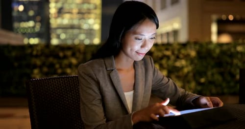 Woman Uses Tablet at Night in Urban Setting