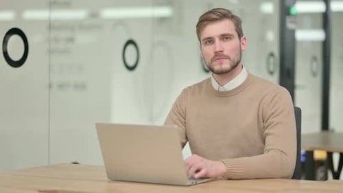 Man Typing on Laptop in Modern Office