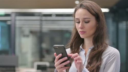 Woman Confused by Smartphone in Office Environment