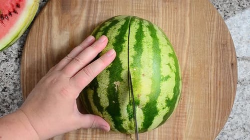Person Cutting a Watermelon in Half
