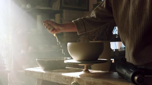 Potter retire l'eau d'un bol en argile crue
