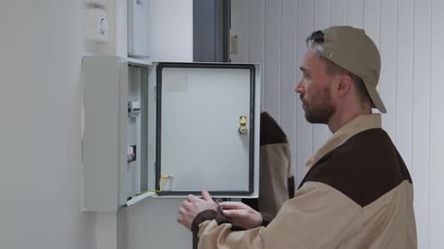 Man Troubleshooting Electrical Panel with a Screwdriver