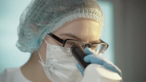 Woman Using Microscope in a Medical Lab