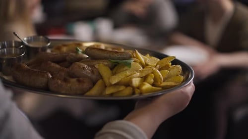 Live Camera Follows Tray with Grilled Potato and Sausages in Waiter Hands Walking to Table with
