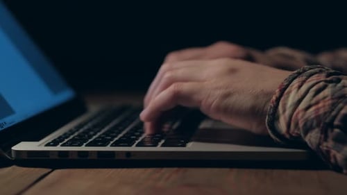 Hände eines Mannes, der nachts am Laptop arbeitet
